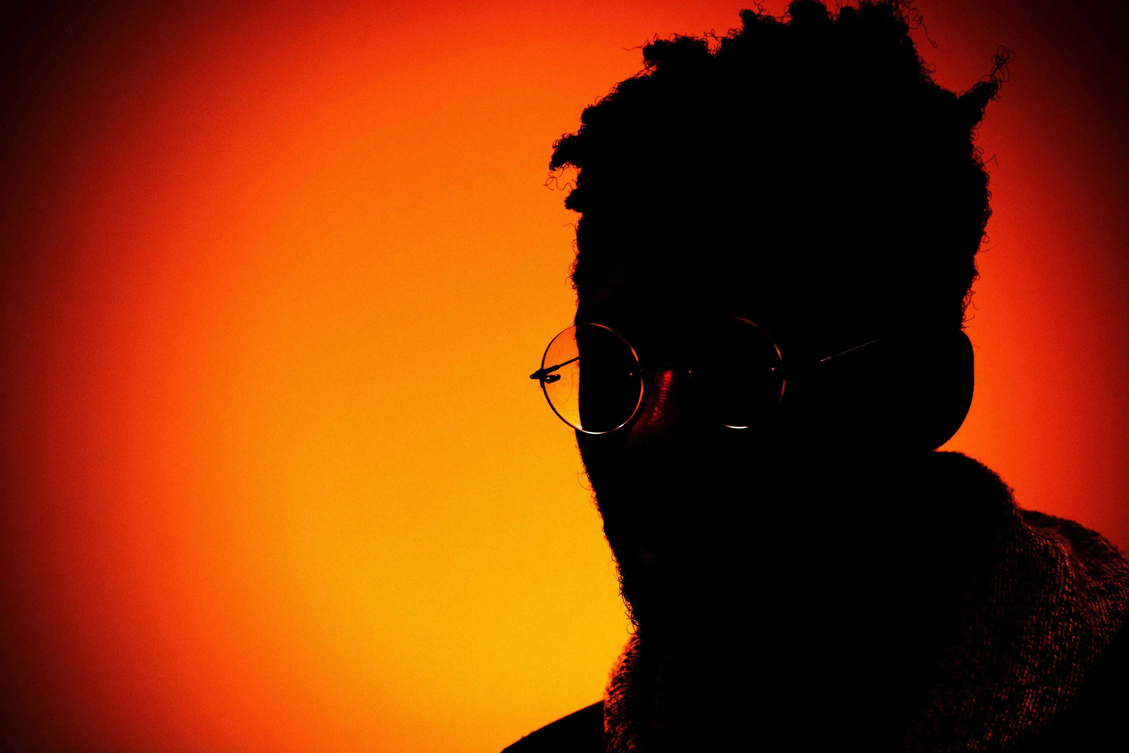 Silhouette portrait of an artist against an orange background